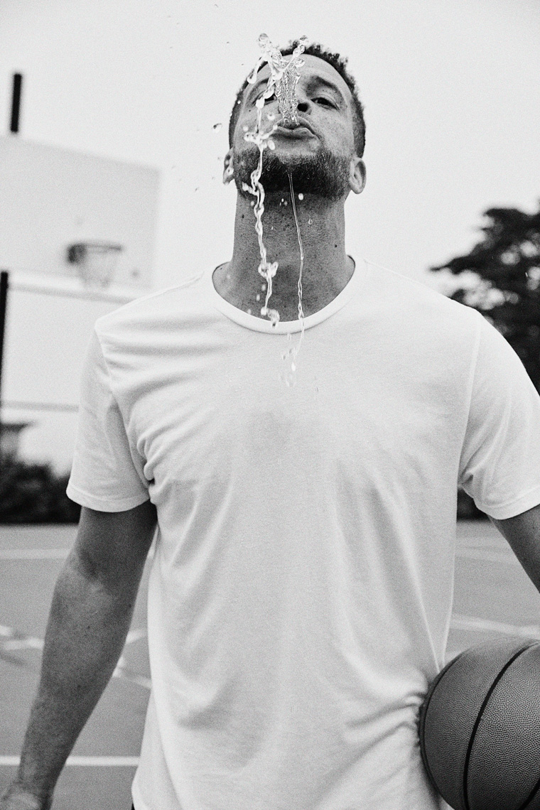 Man playfully spitting water at camera with basketball