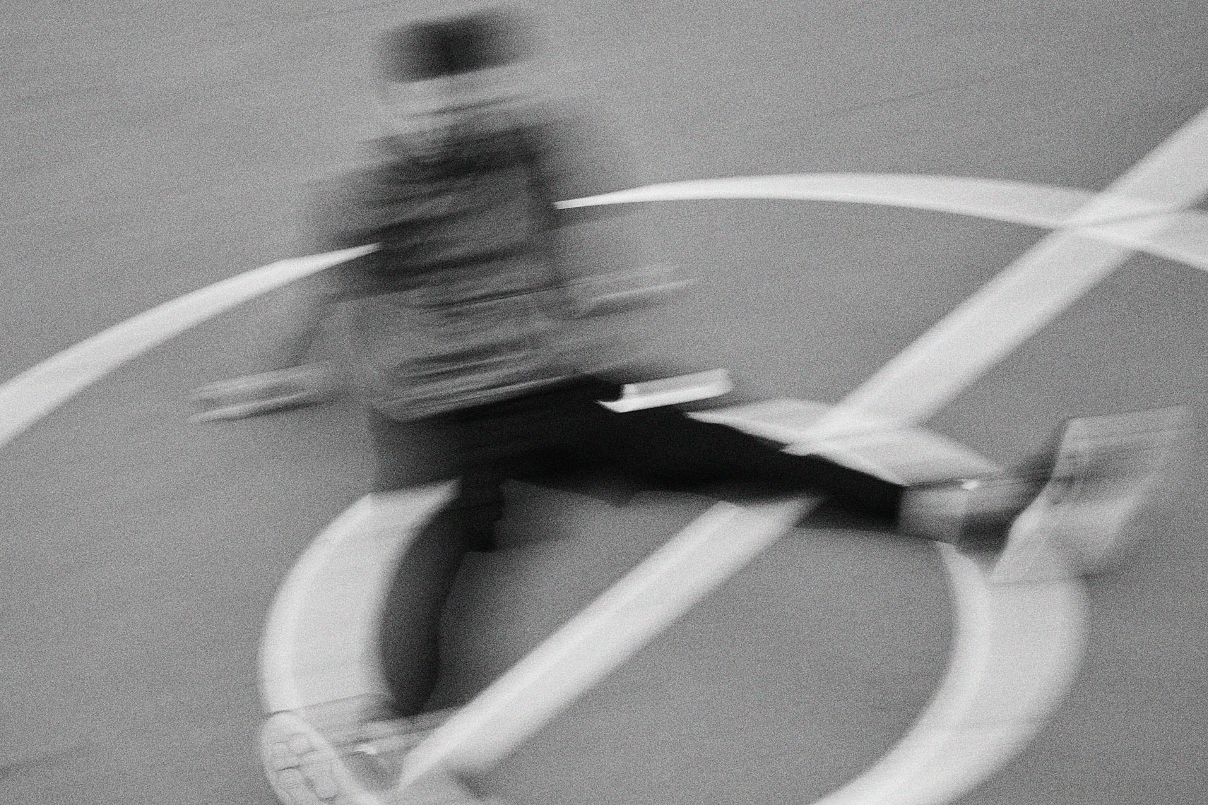 Blurry black and white image of man sitting on basketball court