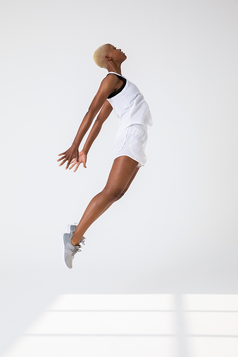 Portrait of non-binary African American mode jumpingl in white activewear in white studio 