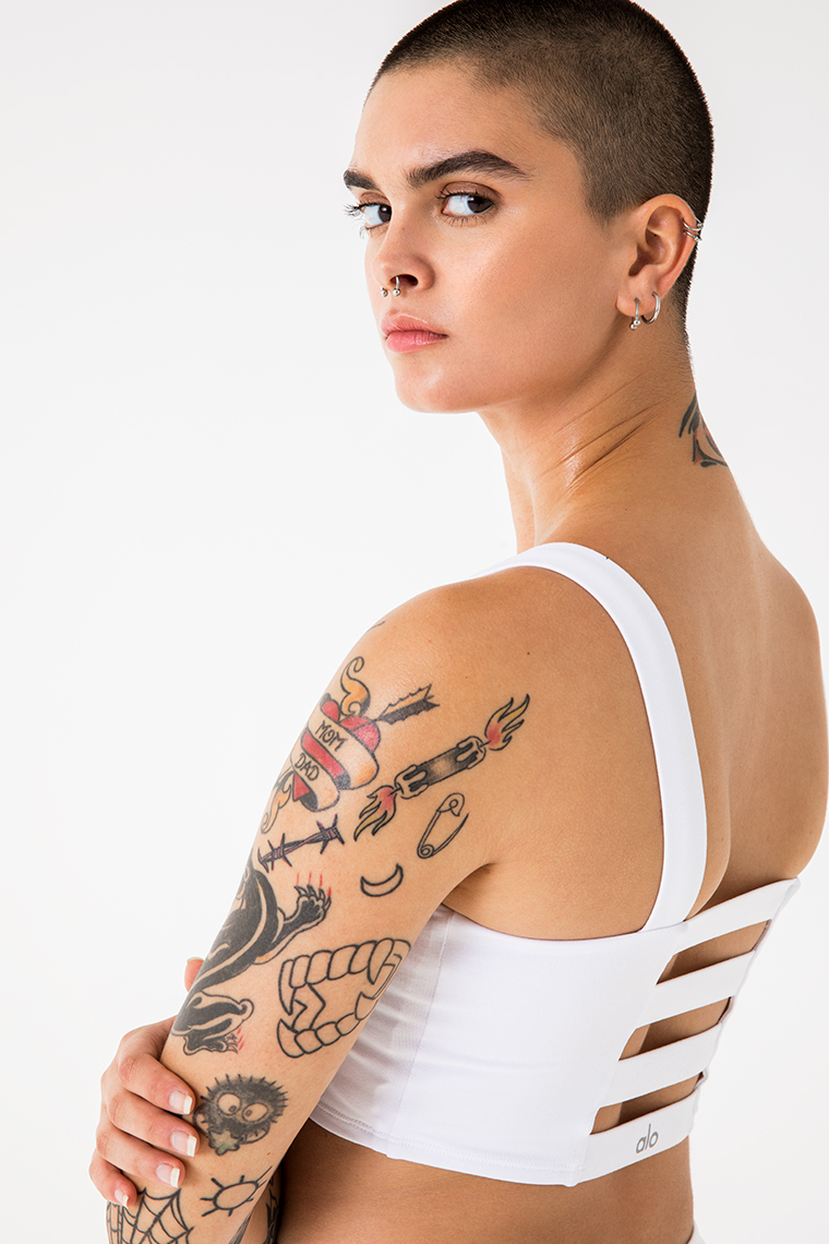 Portrait of woman with shaved head and tattoos  in sports bra 