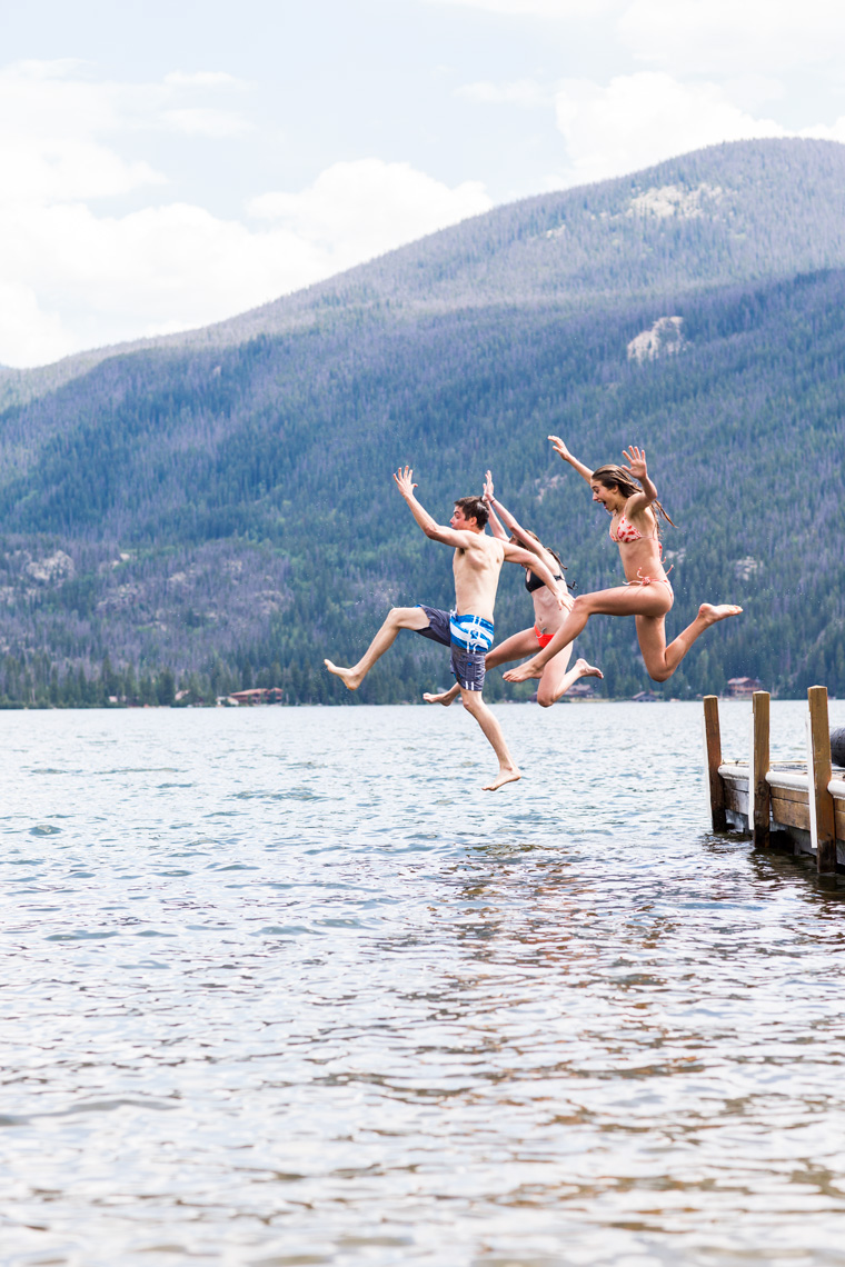 Friends jumping off a dock into a lake